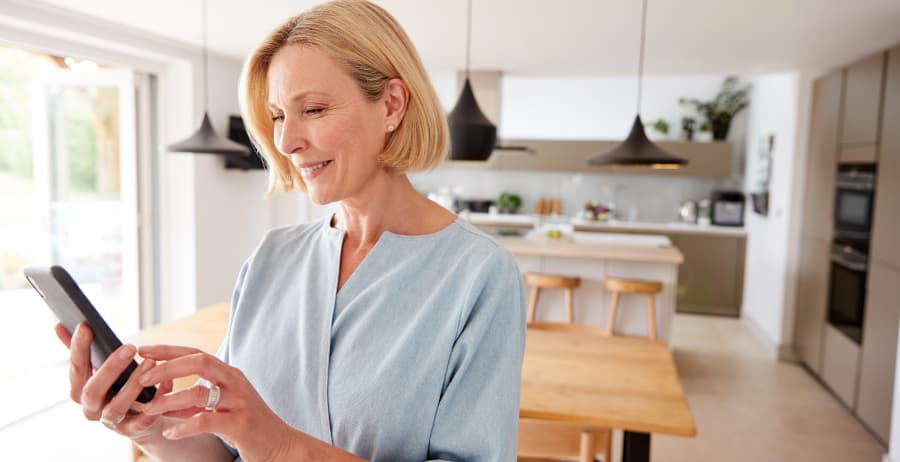 Homeowner with mobile device in a room filled with sunlight